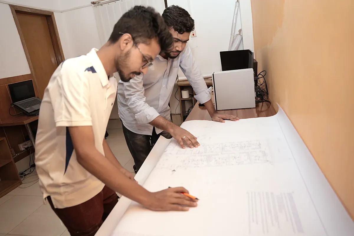 Two colleagues reviewing a large printed drawing on a desk